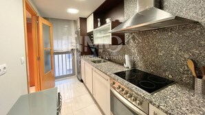 A modern kitchen with granite countertops, stainless steel appliances, and a sliding glass door leading to a balcony. - Apartament in Edif. Alba de Cambrils (Cambrils)