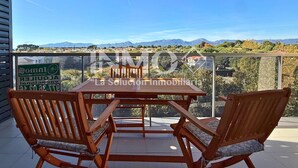A balcony with a wooden table and two chairs, overlooking a mountainous landscape. - Apartament in Edif. Alba de Cambrils (Cambrils)