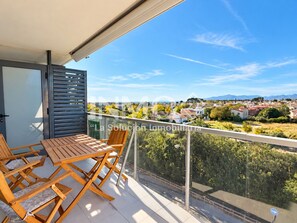 A balcony with a table and chairs, overlooking a residential area with houses and greenery. - Apartament in Edif. Alba de Cambrils (Cambrils)