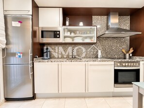A modern kitchen with stainless steel appliances, a microwave, and a built-in oven. - Apartament in Edif. Alba de Cambrils (Cambrils)