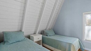 Un dormitorio con dos camas individuales, una mesita de noche y una ventana.