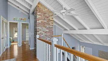 A spacious interior with a high ceiling, a wooden staircase, and a brick fireplace.