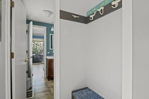 A hallway with a bench, a door leading to a balcony, and a wall-mounted sign. - Contemporary Saltbox In New Seabury! (Mashpee)