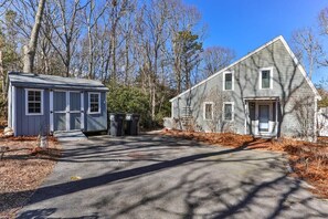 A two-story house with a front porch and a small shed. - Contemporary Saltbox In New Seabury! (Mashpee)