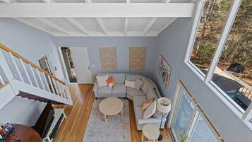 A modern living room with a curved sofa, a round coffee table, and a staircase leading to another level.
