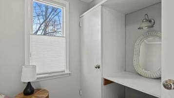 A bathroom with a window, a mirror, and a shelf.