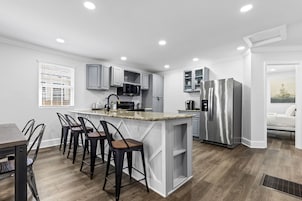 Una cocina moderna con armarios blancos, encimera de granito y electrodomésticos de acero inoxidable.