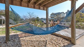 Una hamaca bajo una pérgola de madera, con vista a casas al fondo.