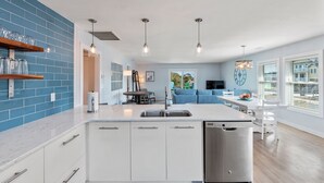 Una cocina moderna con gabinetes blancos, una isla central y salpicadero con azulejos azules.