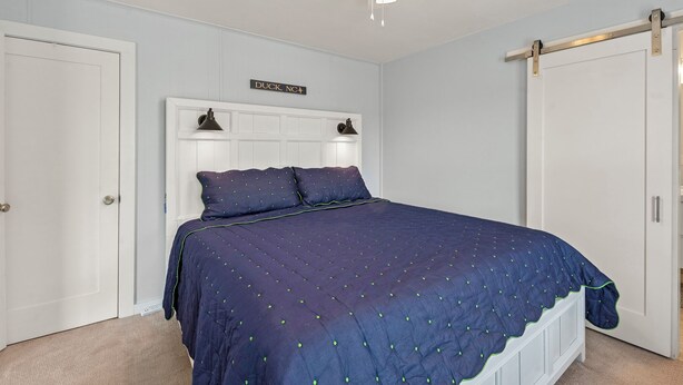 Ein Schlafzimmer mit Bett, Deckenventilator und einer Tür mit einem Schild.