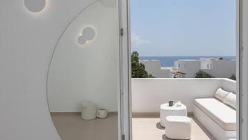 Un interior moderno con un puerta corredera que da a un balcón exterior con un sofá blanco y una pequeña mesa.
