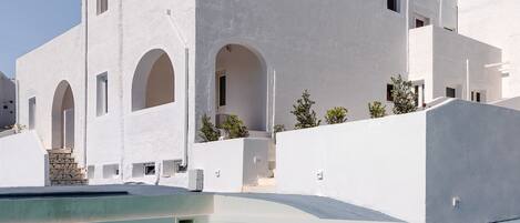 Un edificio blanco con varios arcos y una piscina delantera.
