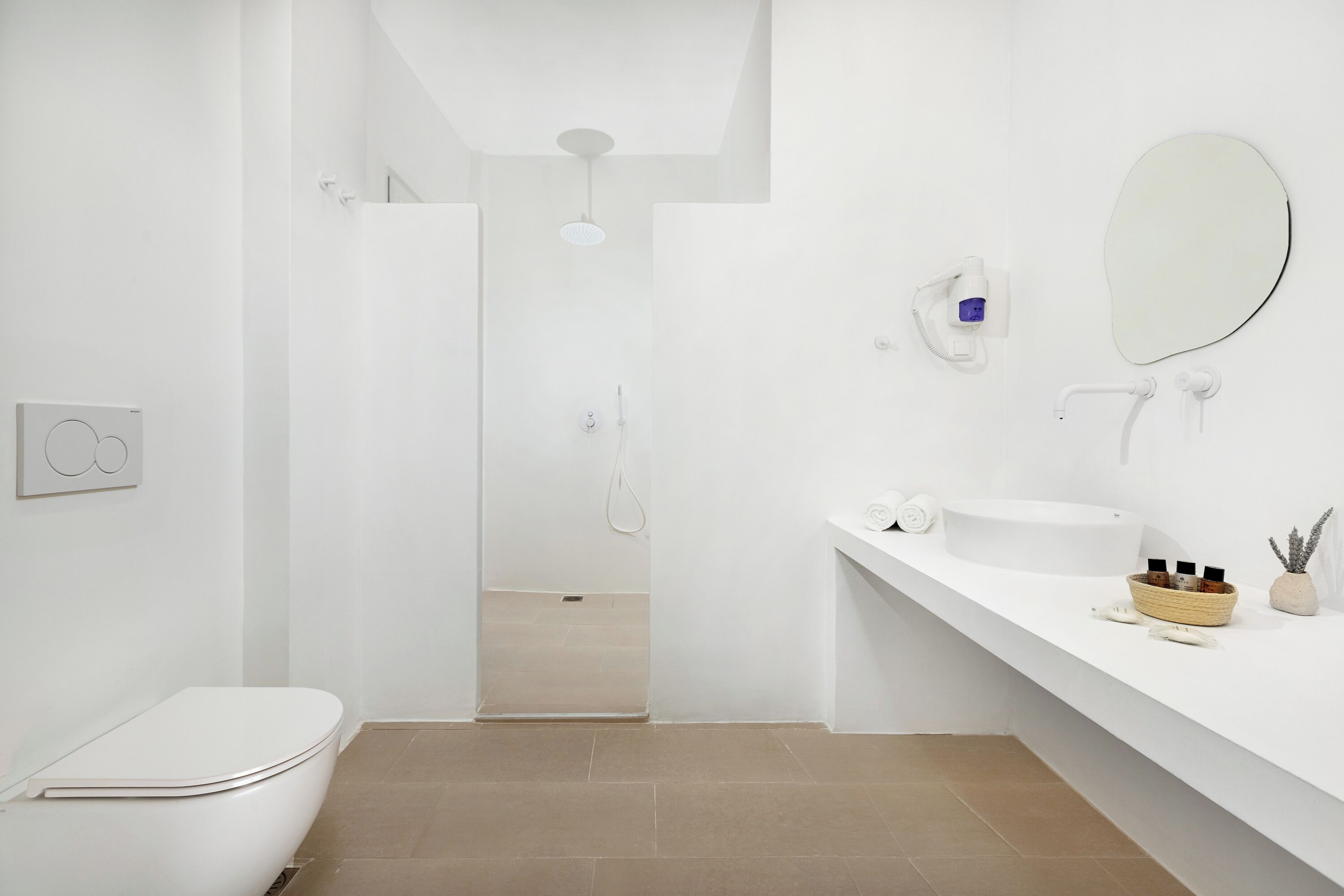 Un baño moderno con inodoro, lavabo, ducha y espejo.