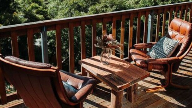 A wooden deck with a view of a lake and trees. - Kelp Cabin - intimate, calm and restful (White Beach)