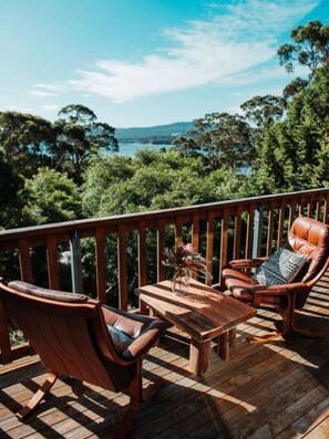 A wooden deck with a view of a lake and trees. - Kelp Cabin - intimate, calm and restful (White Beach)