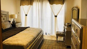 A hotel room with a bed, a nightstand, a dresser, and a mirror.