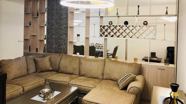 A modern living room with a sectional sofa, a coffee table, and a decorative lamp.