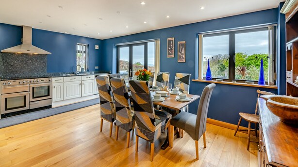 A modern kitchen with white cabinets, a built-in oven, and a large window overlooking a scenic view. - 4 bedroom accommodation in Runswick Bay (Runswick Bay)
