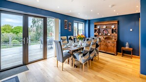 A dining area with a large table set for six, surrounded by chairs with patterned cushions. - 4 bedroom accommodation in Runswick Bay (Runswick Bay)