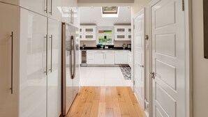 A modern kitchen with white cabinetry, a central island, and a skylight. - Luxurious yet cosy Family home (London)
