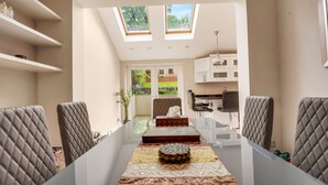 A modern kitchen with a dining area, skylights, and a view of the garden. - Luxurious yet cosy Family home (London)