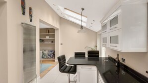 A modern kitchen with a black countertop, white cabinets, and a skylight. - Luxurious yet cosy Family home (London)