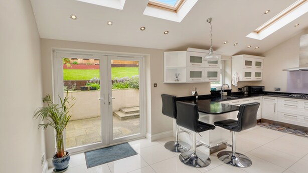 A modern kitchen with a central island, white cabinets, and a skylight. - Luxurious yet cosy Family home (London)
