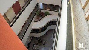 Un atrium à plusieurs niveaux doté d’un jardin central, d’un escalier en courbe et d’un espace détente avec des tables et des chaises.