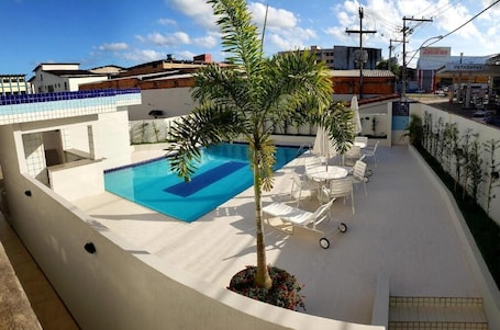 Una piscina al aire libre, sombrillas, sillones reclinables de piscina