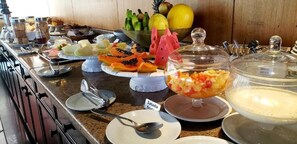 Ein Buffet mit verschiedenen Früchten und einem Schild mit der Aufschrift 'Salada fruit'.