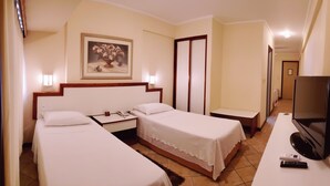 Une chambre d’hôtel avec deux lits, un bureau, une télévision et un tableau au mur.