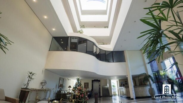 Un hall d’hôtel spacieux, doté d’un plafond haut, d’un atrium central et de plusieurs niveaux.