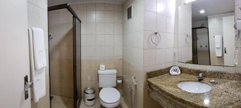 A bathroom with a toilet, sink, and shower.