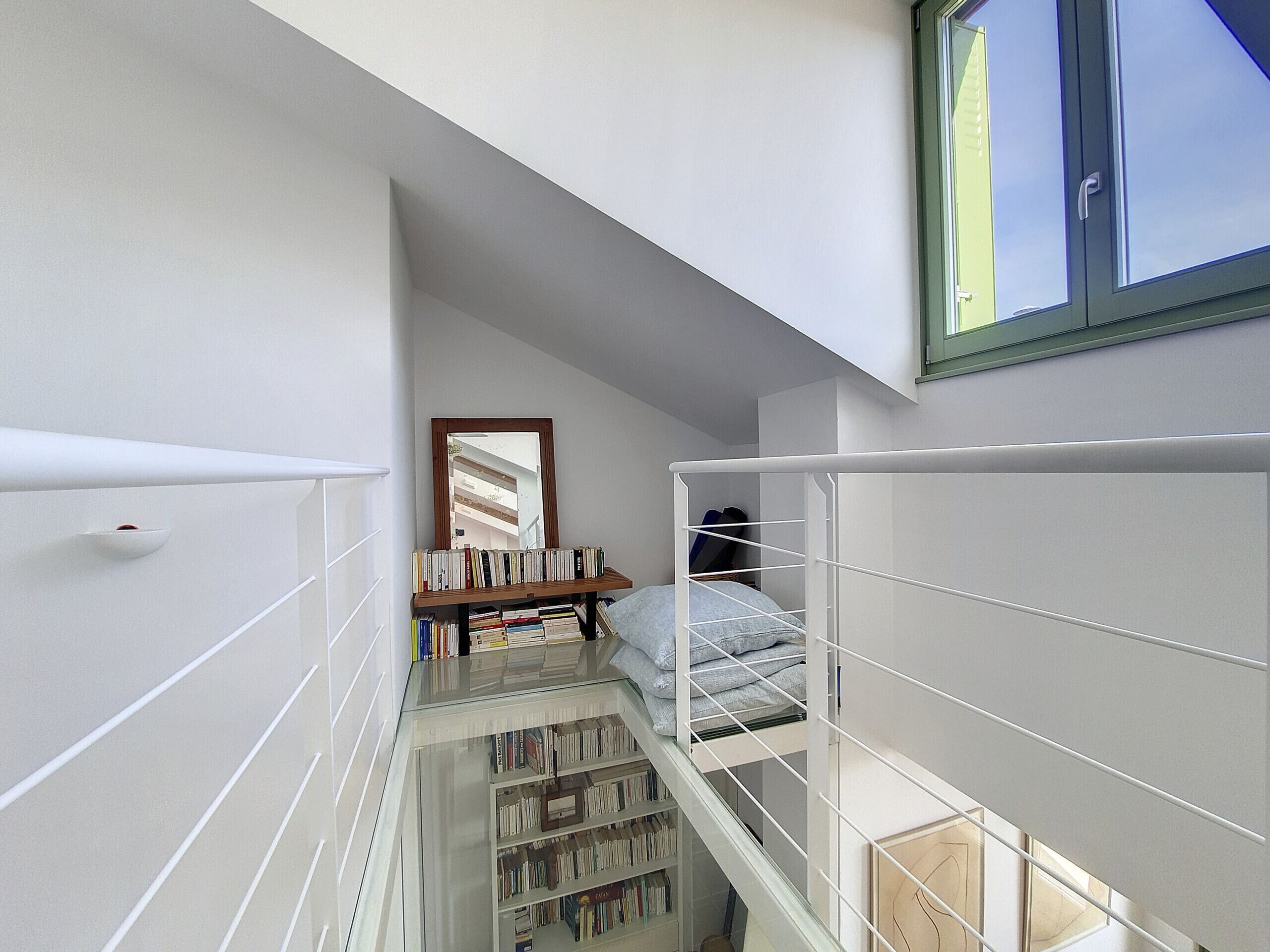 A narrow room with a bunk bed, a bookshelf, and a mirror.