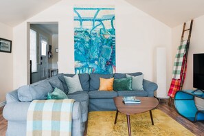 Un salon avec un canapé gris, une table basse et un fauteuil bleu.