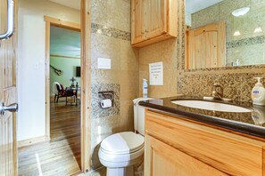 Un bagno con il water, un lavandino e armadietti in legno.