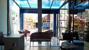 A room with a glass door leading to an outdoor area, wicker furniture, and a tiled floor. - Hotel rios  (Jaguarao)