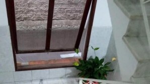 Un escalier en marbre agrémenté de bandes de sécurité rouges, un pot de fleurs et une fenêtre avec un mur à texture.