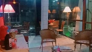 Un hall d’hôtel avec des portes en verre, plusieurs chaises et des tables.