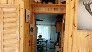 Un intérieur en bois avec une porte donnant sur un coin repas, une petite table avec des chaises et un réfrigérateur.