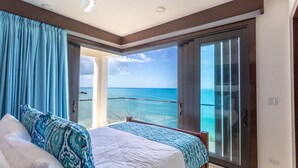 Ein Hotelzimmer mit Bett, einem großen Fenster und Blick auf den Ozean.