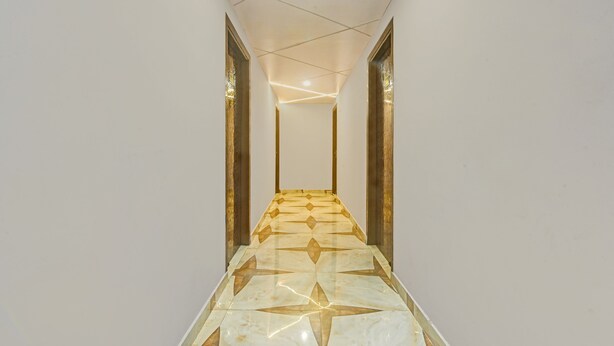 A hallway with a geometric patterned floor, white walls, and a ceiling with recessed lighting. - Itsy Hotels Palacio (Kanpur)