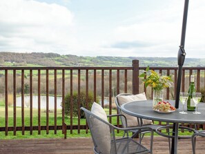 En terrasse med et bord dækket til to, med udsigt over et naturskønt landskab.