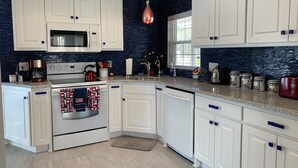 A modern kitchen with white cabinetry, a stainless steel range, a microwave, and a red kettle. - Island Trail's Sunset Cottage on Beautiful Lake Murray - Now with King Size bed! (Chapin)