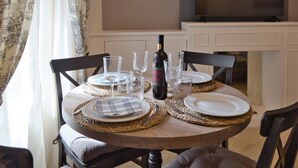 Une table à manger dressée avec des assiettes, des verres et une bouteille, entourée de chaises dotées de coussins.