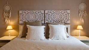Un lit bien fait, avec une literie blanche, deux tables de chevet avec des lampes et une tête de lit décorative.