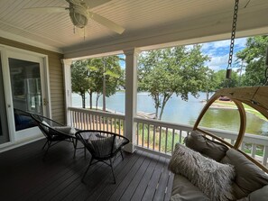 A covered porch with a view of a lake, two chairs, and a swing seat. - Direct Lake-Luxury Home w/ Dock Access – Reynolds, Lake Oconee- Near The Masters (Greensboro)