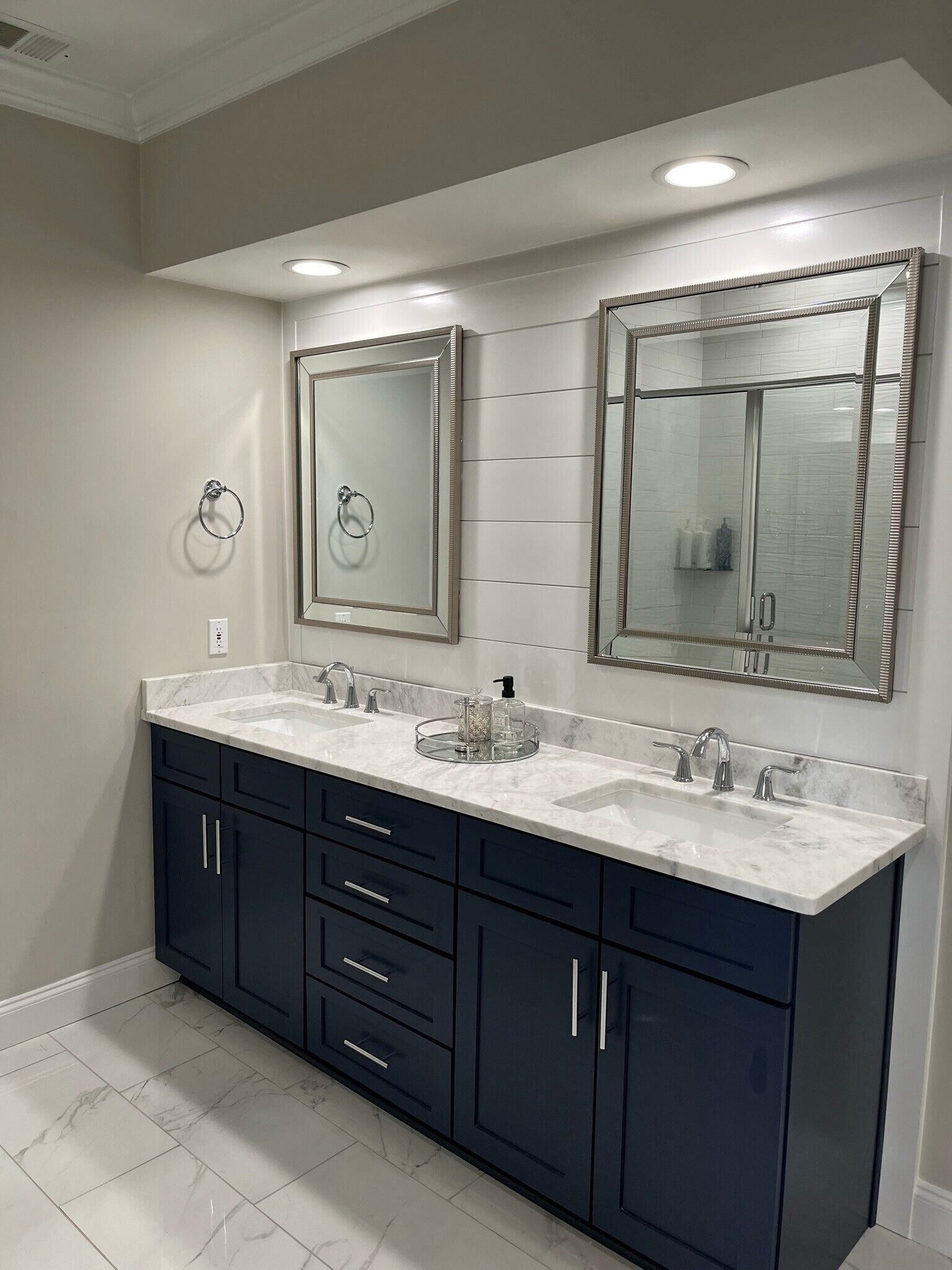 A modern bathroom with two sinks, dark cabinets, and large mirrors.