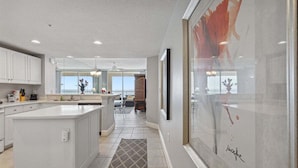 A modern kitchen with white cabinetry, a central island, and a dining area with a view.