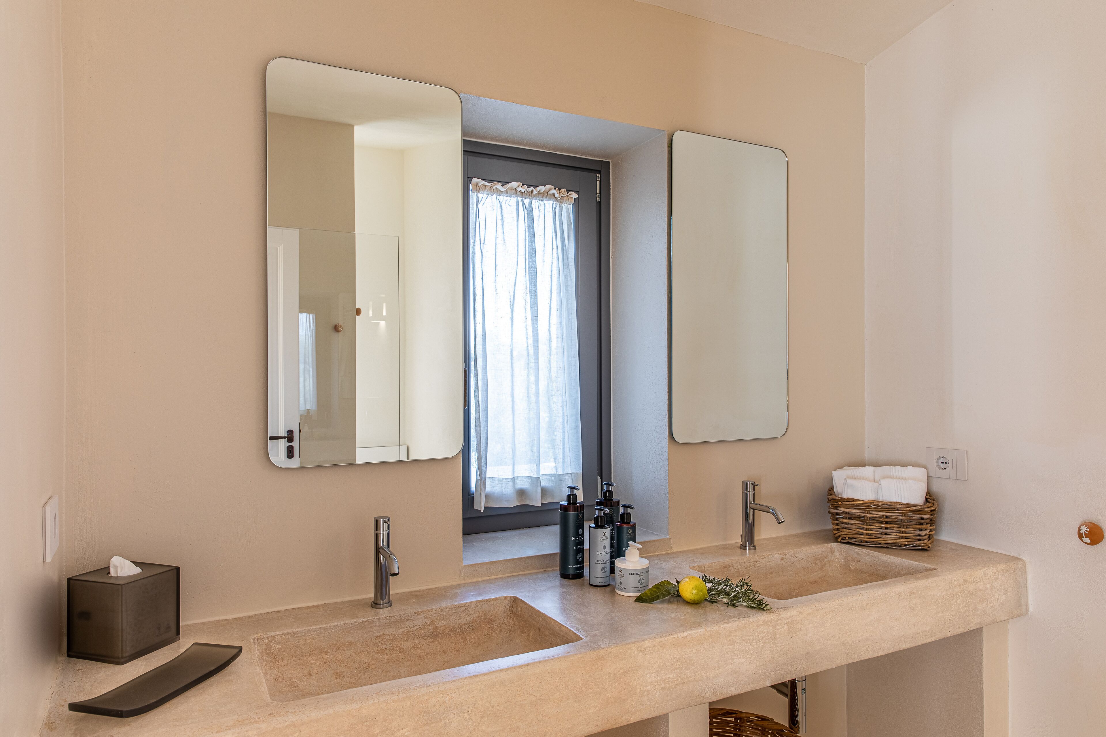 A bathroom with two sinks, a mirror, and a window with curtains.